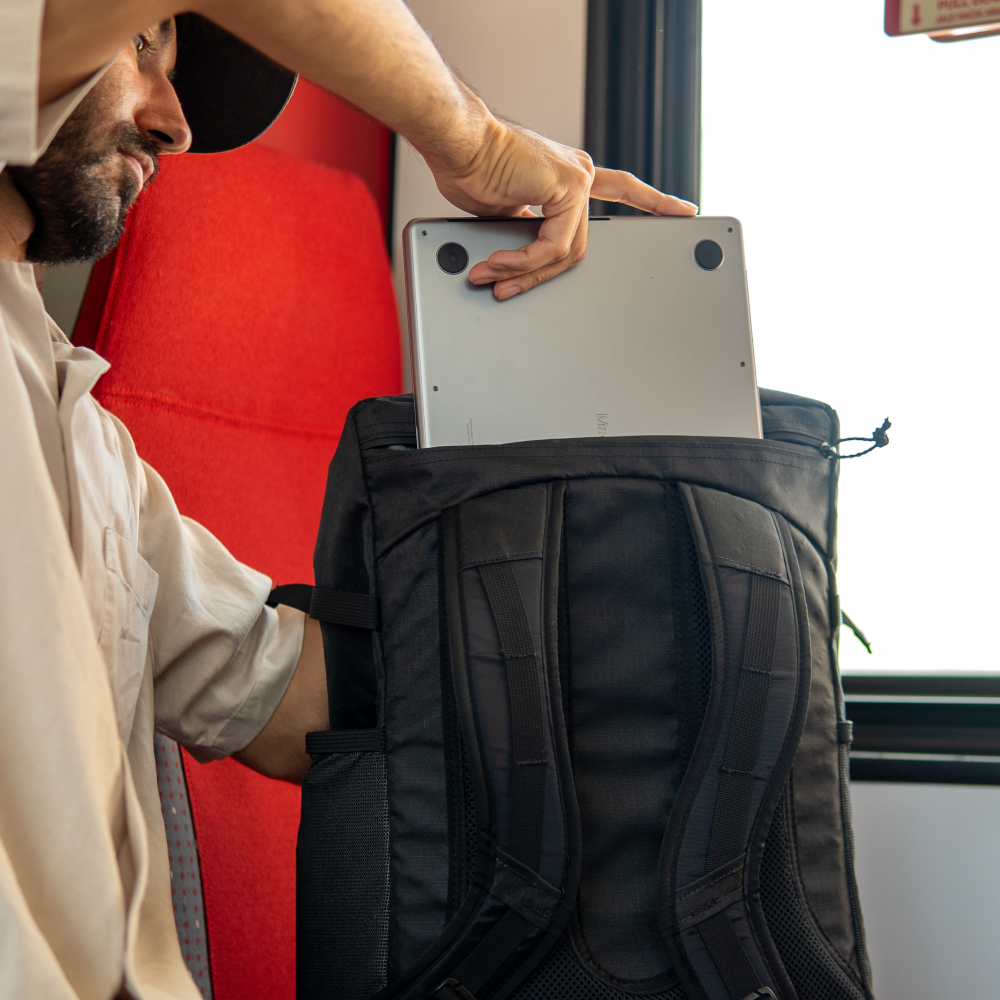Man on train puts 17" laptop into ULA EcoPak 36L Dragonfly
