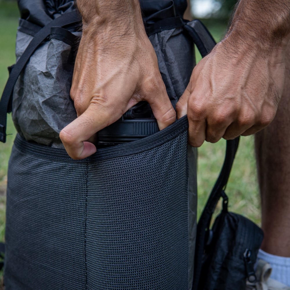 Hiker wears water-resistant ULTRA Spare Tire Waist Pack in Rain