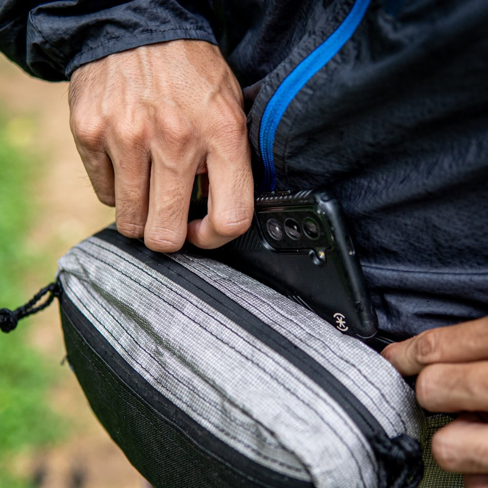 Hiker tucks phone into elastic topped mesh hind pocket