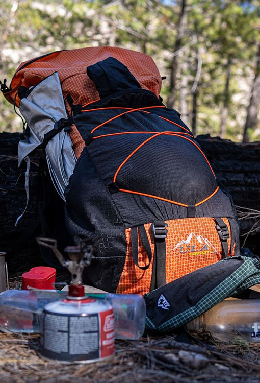 Backpacker puts a Bear Vault Bear Canister into a ULA CDT Backpack