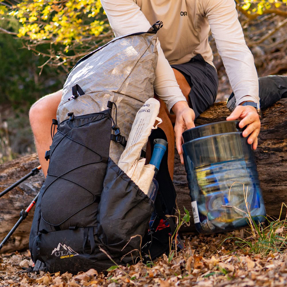 Backpacker tightens top y-strap of Circuit over bear canister