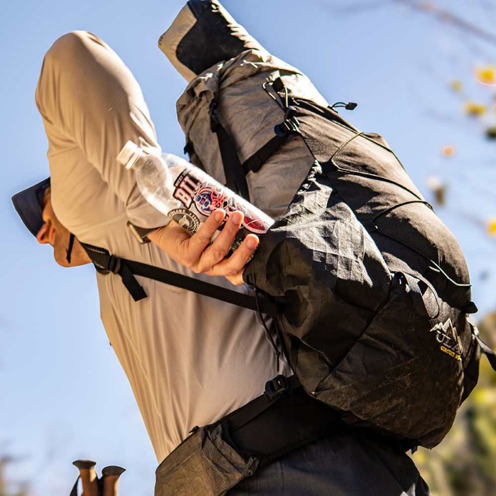 Backpacker on the trail with a ULA Circuit with Bottom Straps carrying a sleeping pad