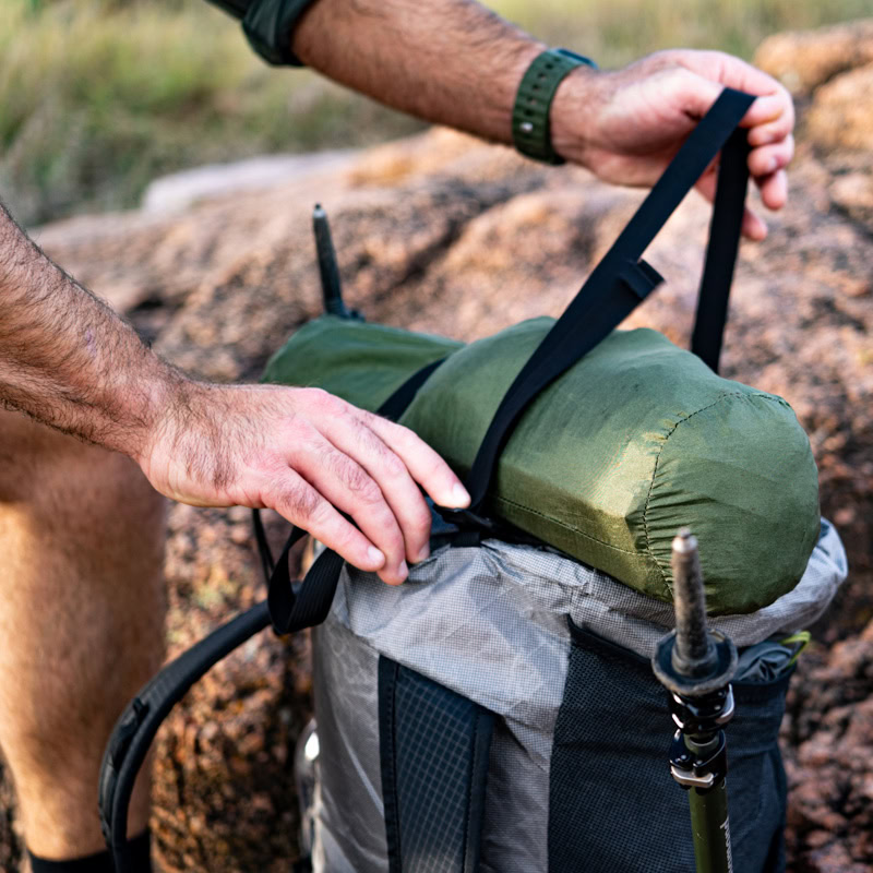 Backpacker tightens top y-strap of Circuit over bear canister