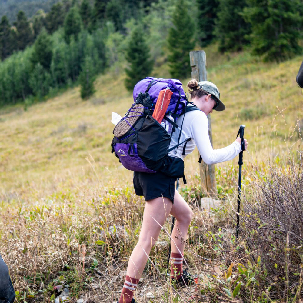 Backpacker setting up camp with his red Catalyst backpack in the foreground