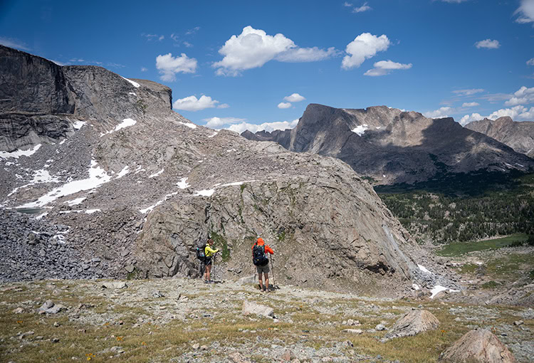 Backpacker reaches for his bear spray from the ULA Deploy Bear Canister Holder on his shoulder strap.