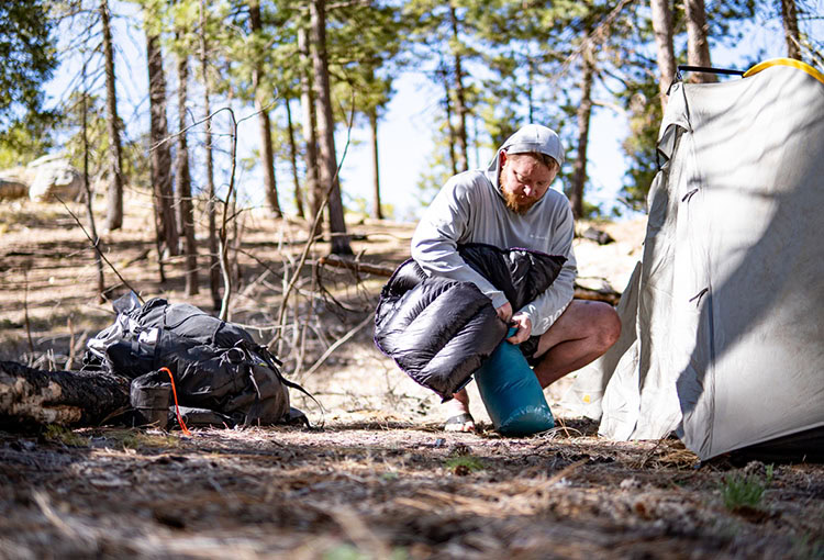 Backpacker sitting on a BearVault. The BearVault also makes an excellent chair. 