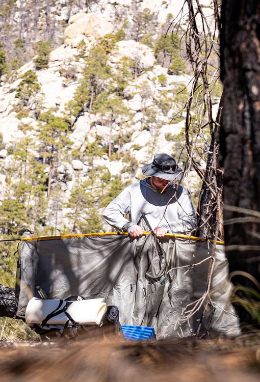 A BearVault being opened by a hiker. The BearVault also keeps your snacks from getting crushed.